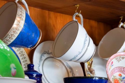 Teacups hanging from a china cabinet