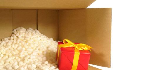 A wrapped present being shipped in a brown box with peanuts