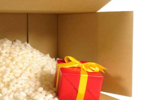 A wrapped present being shipped in a brown box with peanuts